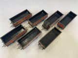 six wagons de train miniature alignés les uns à côté des autres sur une surface blanche