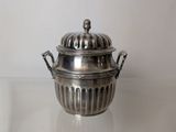 a silver plate with a lid on a glass table