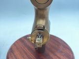an image of a small brass object on a wooden base