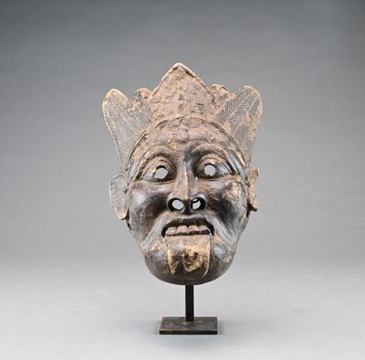 sculpture représentant le visage d'un homme, posée sur un socle, avec un fond gris
