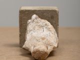 a small rock sitting on a table next to a block of cement