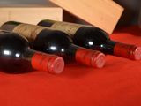 several bottles of wine are lined up on a red table cloth