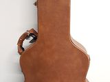a brown guitar case sitting on the floor next to a white wall