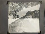 a black and white photo of a plane flying over a city