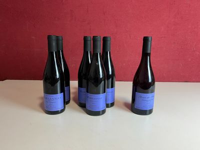 trois bouteilles de vin sont posées sur une table devant un mur rouge