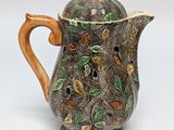a brown and green coffee pot with leaves on it