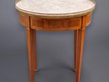 une table ronde avec un plateau en marbre et des pieds en bois