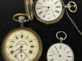 Trois types différents de montres de poche sont exposés sur un fond noir