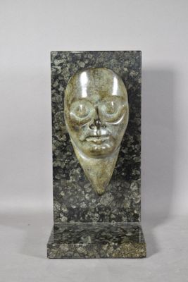 a close up of a sculpture of a face on a marble block