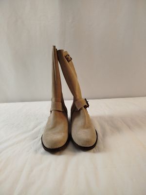 une paire de chaussures beiges posées sur un lit blanc, sur fond blanc