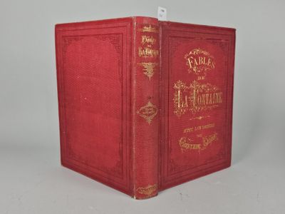 an old red book sitting on top of a table next to a white wall