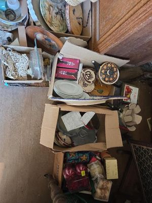 boxes of assorted items sit on the floor in a cluttered room