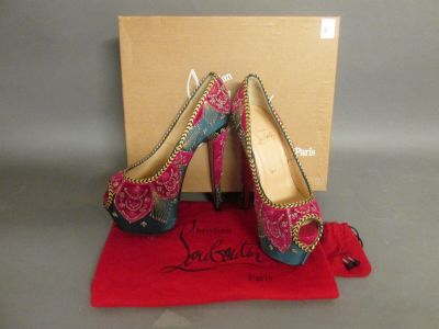 une paire de chaussures à talons hauts roses et bleues posées sur un tissu rouge