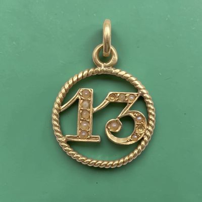 un pendentif en or sur lequel est gravé le chiffre treize