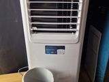 a small air conditioner sitting on a table next to a cup