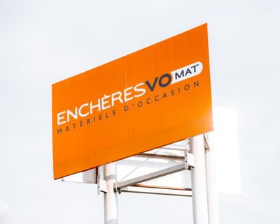 un panneau orange sur lequel est écrit « encheres vomat »