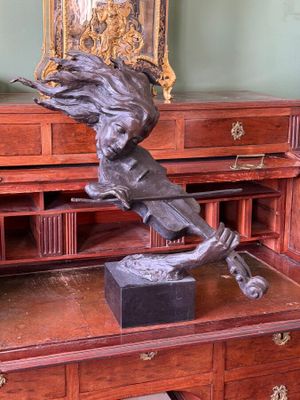 a bronze statue of a bird on top of a desk