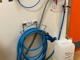 un tuyau bleu fixé au mur, à côté d'un récipient blanc