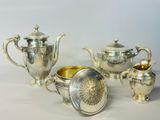 un service à thé en argent posé sur une table, avec une tasse et une soucoupe