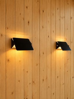 deux lampes noires fixées à un mur en bois dans une pièce aux murs lambrissés
