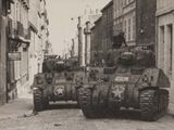 une photo en noir et blanc montrant deux chars dans une rue de la ville