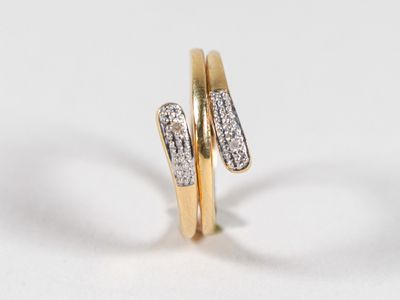 une image représentant deux bagues en or serties de diamants, posées sur une surface blanche