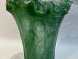 a green vase that is sitting on a white cloth
