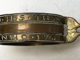 un gros plan d'un bracelet en laiton sur lequel figure un prénom
