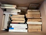 a lot of books in a cardboard box on the floor