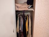 une armoire avec des vêtements suspendus à l'intérieur, dans une petite pièce
