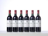 four bottles of red wine are lined up on a table