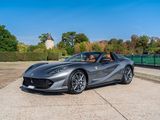 a grey ferrari sports car parked in front of a park