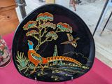 une assiette noire sur laquelle sont représentés un faisan et des fleurs