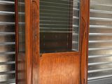une vieille armoire en bois munie d'une porte vitrée