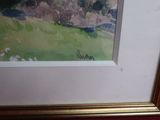 framed picture of a painting of a green field with trees in the background