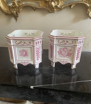 une paire de pots de fleurs en porcelaine rose et blanche posés sur une table noire