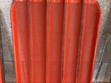 un radiateur rouge posé sur le sol à côté d'un mur de briques