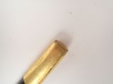 a close up of a gold colored pencil on a white surface