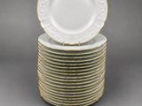 a stack of white and gold dinner plates with gold rims