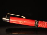 a red pen with writing on it sitting on a black surface