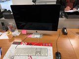 a woman sitting at a desk with a computer monitor and keyboard