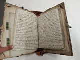 someone is holding an old book open with writing on it