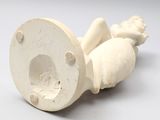 porcelain figurine of a baby laying on its back on a white surface
