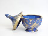 a blue bowl with a gold lid on a white surface