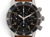 La montre possède un cadran noir et un bracelet en cuir marron.
