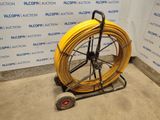 a yellow hose on a cart in front of a wall