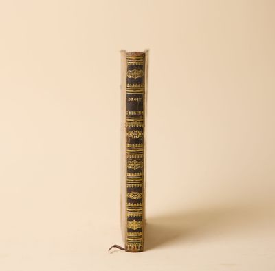 un vieux livre posé sur une table à côté d'un mur blanc