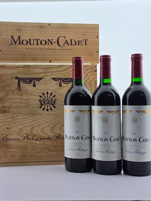 trois bouteilles de vin rouge sont posées devant une caisse en bois