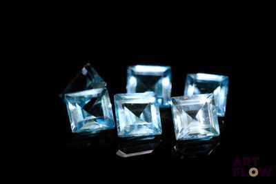 three pieces of blue topazte on a black surface