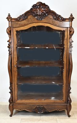 une bibliothèque ancienne en bois avec des étagères en verre, posée sur un sol carrelé